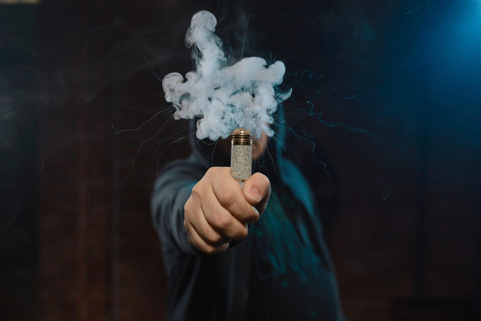 Dripper in one hand making a cloud of fume Dripper in one hand making a cloud of white, blue vapours. Friendly for vape shop posters and design. Vaping concept.